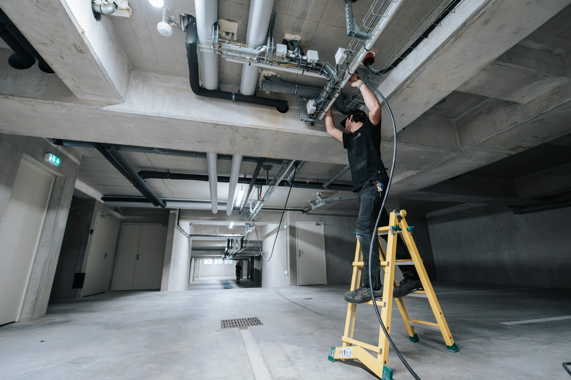 PHOTO D'UN ÉLECTRICIEN EN PLEINE INTERVENTION DANS UN GARAGE COLLECTIF