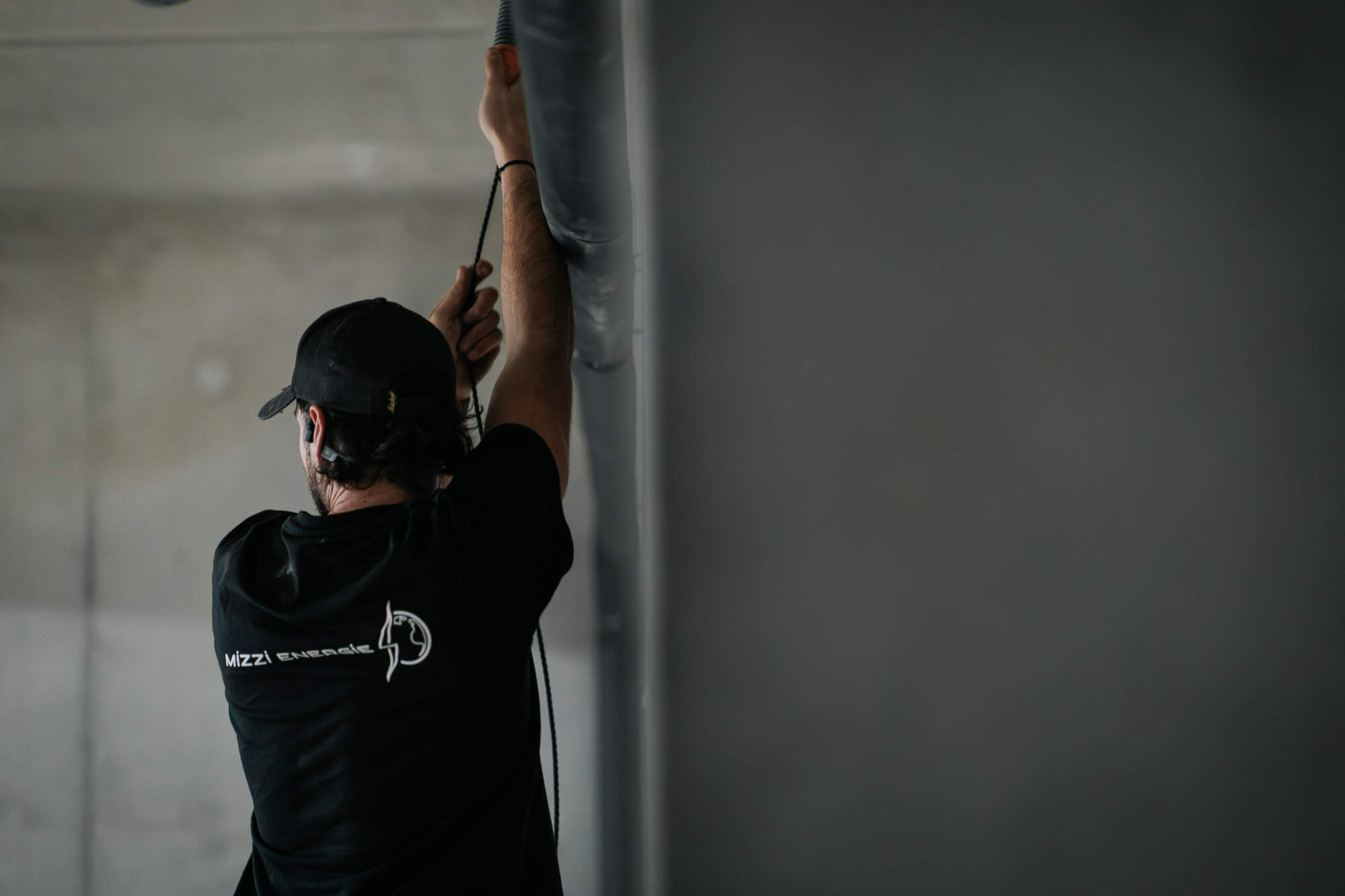 PHOTO D'UN ÉLECTRICIEN ENTRAIN DE TIRER U CÂBLE ÉLECTRIQUE