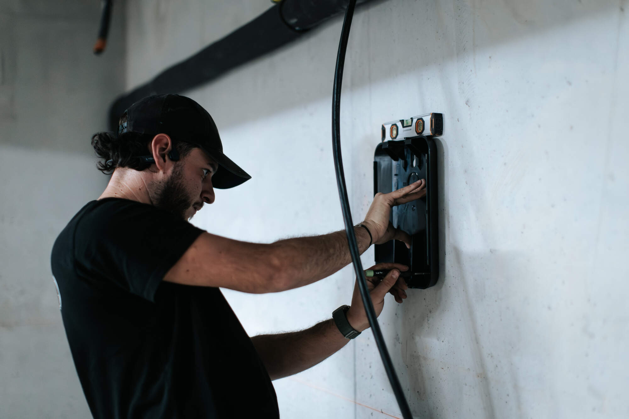 PHOTO D'UN ÉLECTRICIEN ENTRAIN D'INSTALLER UN BOÎTIER ÉLECTRIQUE