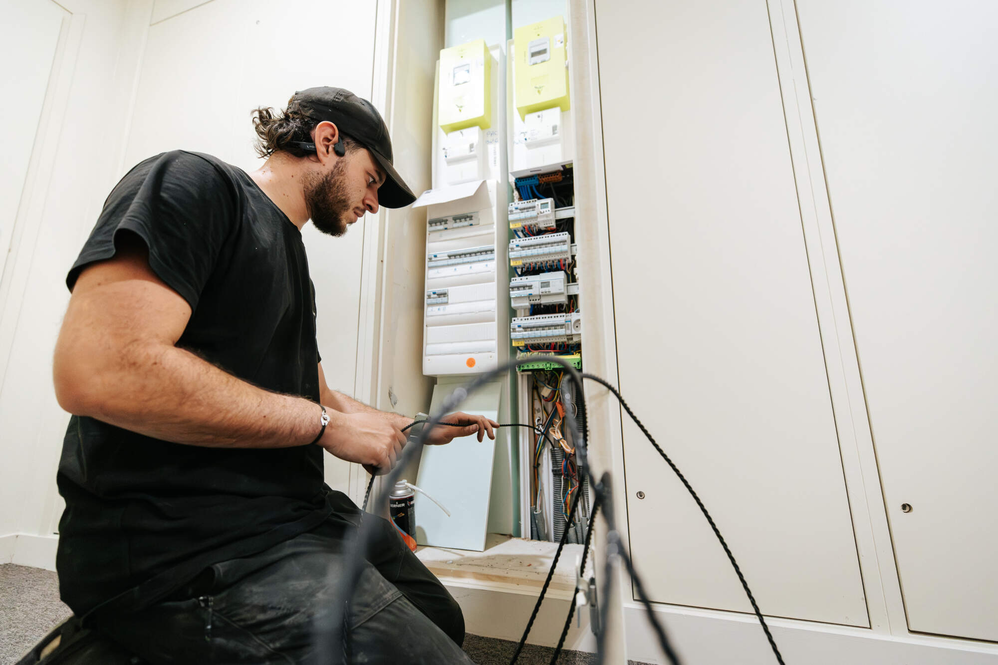 PHOTO D'UN ÉLECTRICIEN ENTRAIN DE RÉPARER UN SYSTÈME CENTRAL D'ÉLECTRICITÉ GÉNÉRALE DANS UN IMMEUBLE