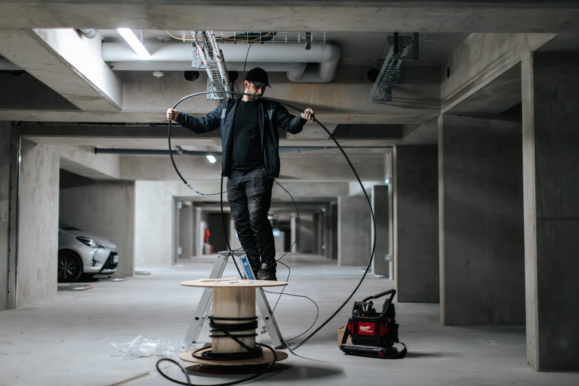 PHOTO D'UN ÉLECTRICIEN SUR UN ESCABEAU ENTRAIN DE TENIR UN CÂBLE ÉLECTRIQUE